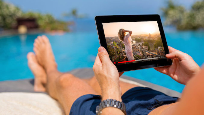 Man watching movie on tablet by the pool.